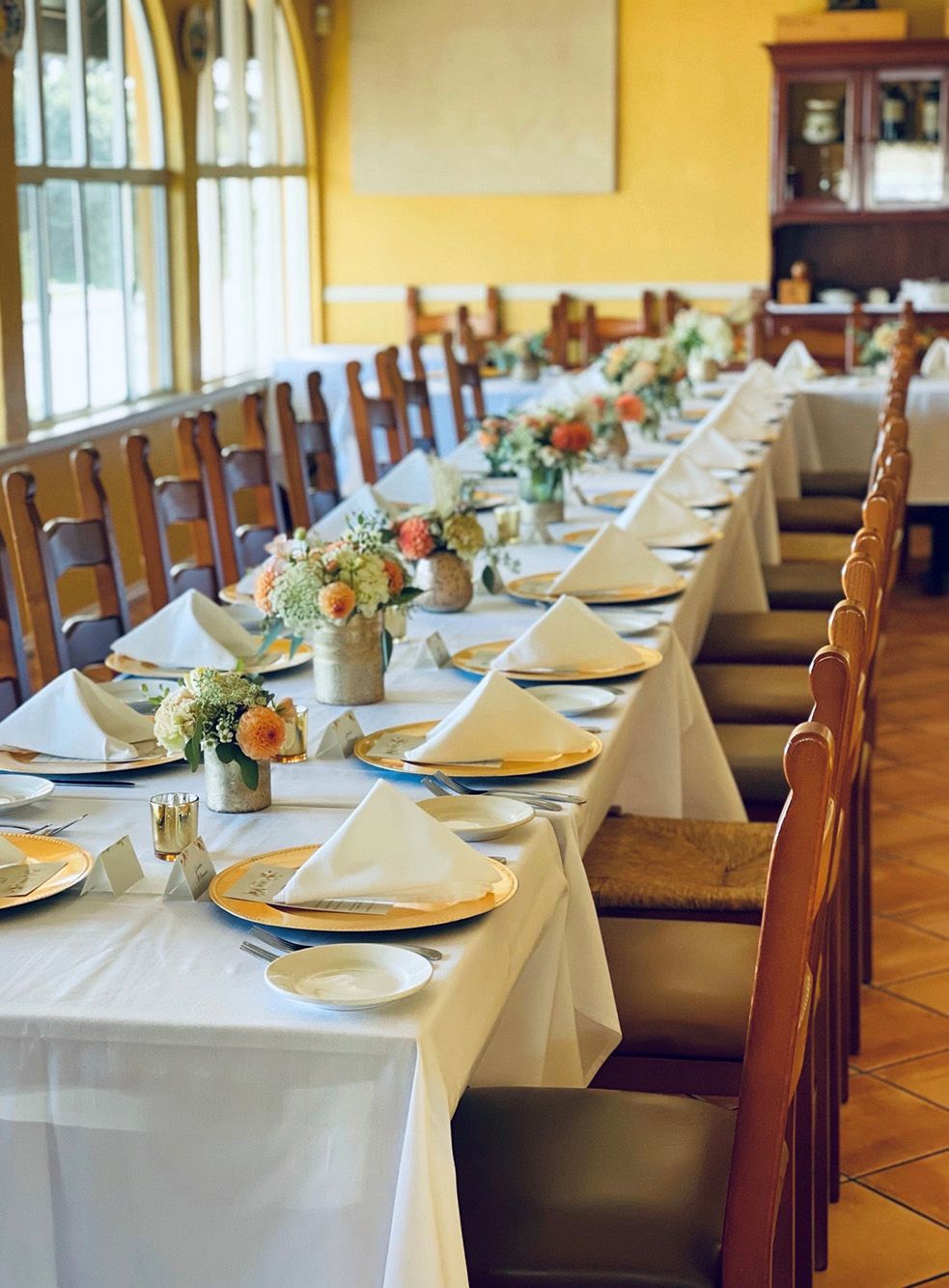 mezzaluna small banquet room showing long table with gold chargers, small floral arrangements, and candles