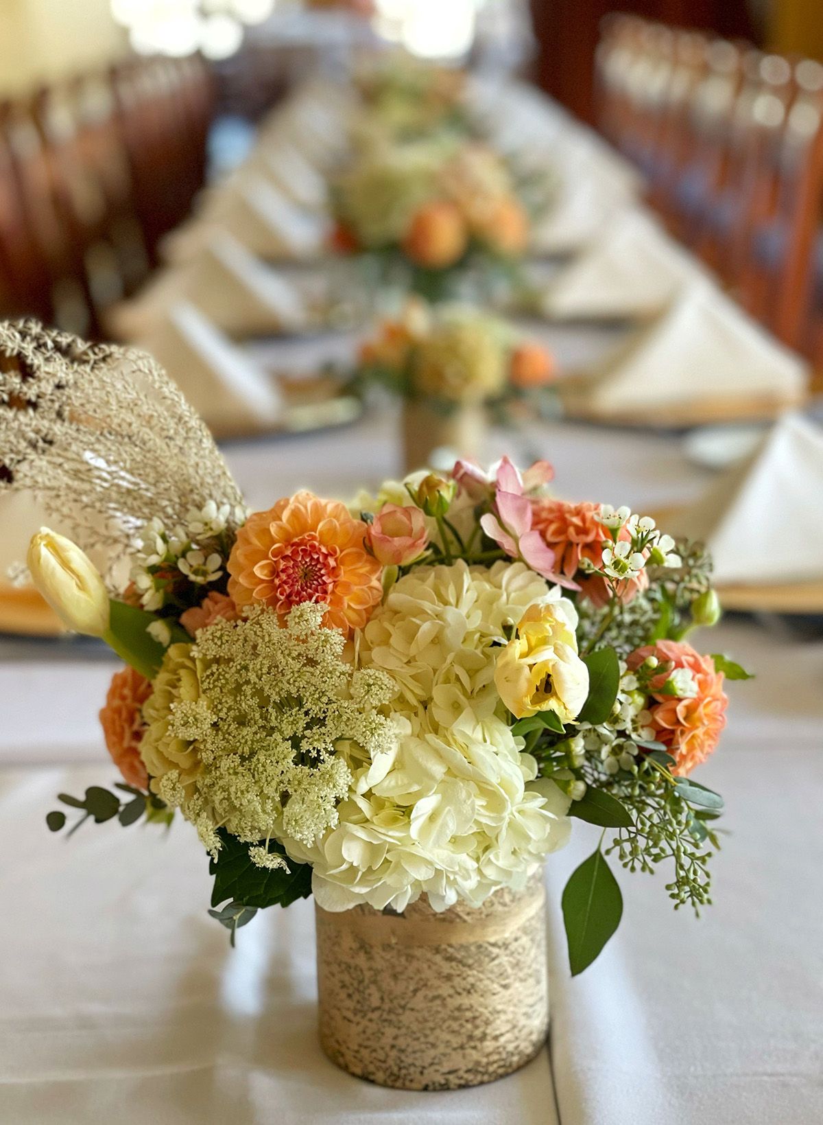 cream and orange flower arrangement on a table in the large banquet room