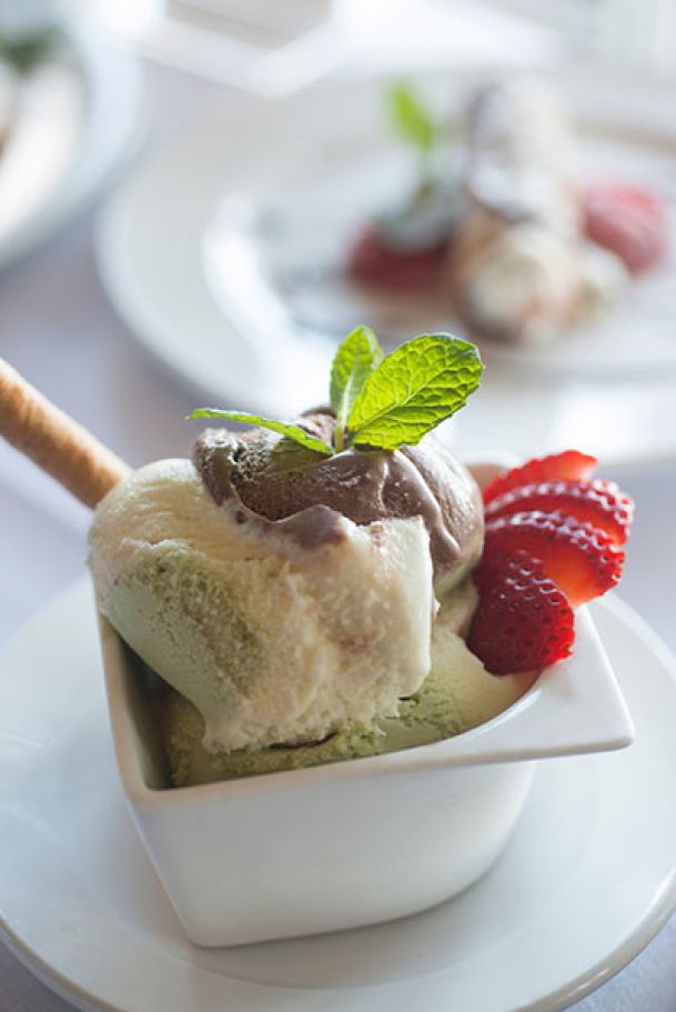 tri-flavor gelati with wafer cookie and strawberries and mint leaves in small white bowl
