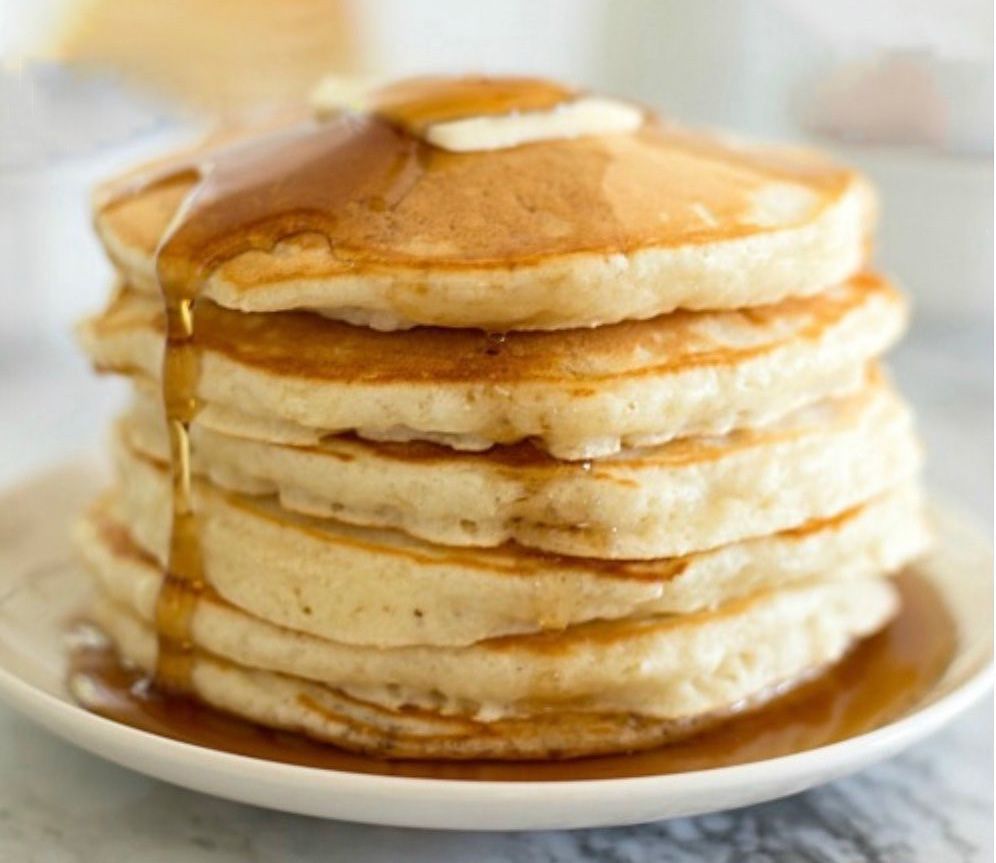 stack of 6 pancakes with butter melting on top and syrup drizzled down sides